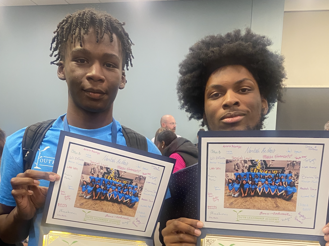 photo of two male students holding up certificates